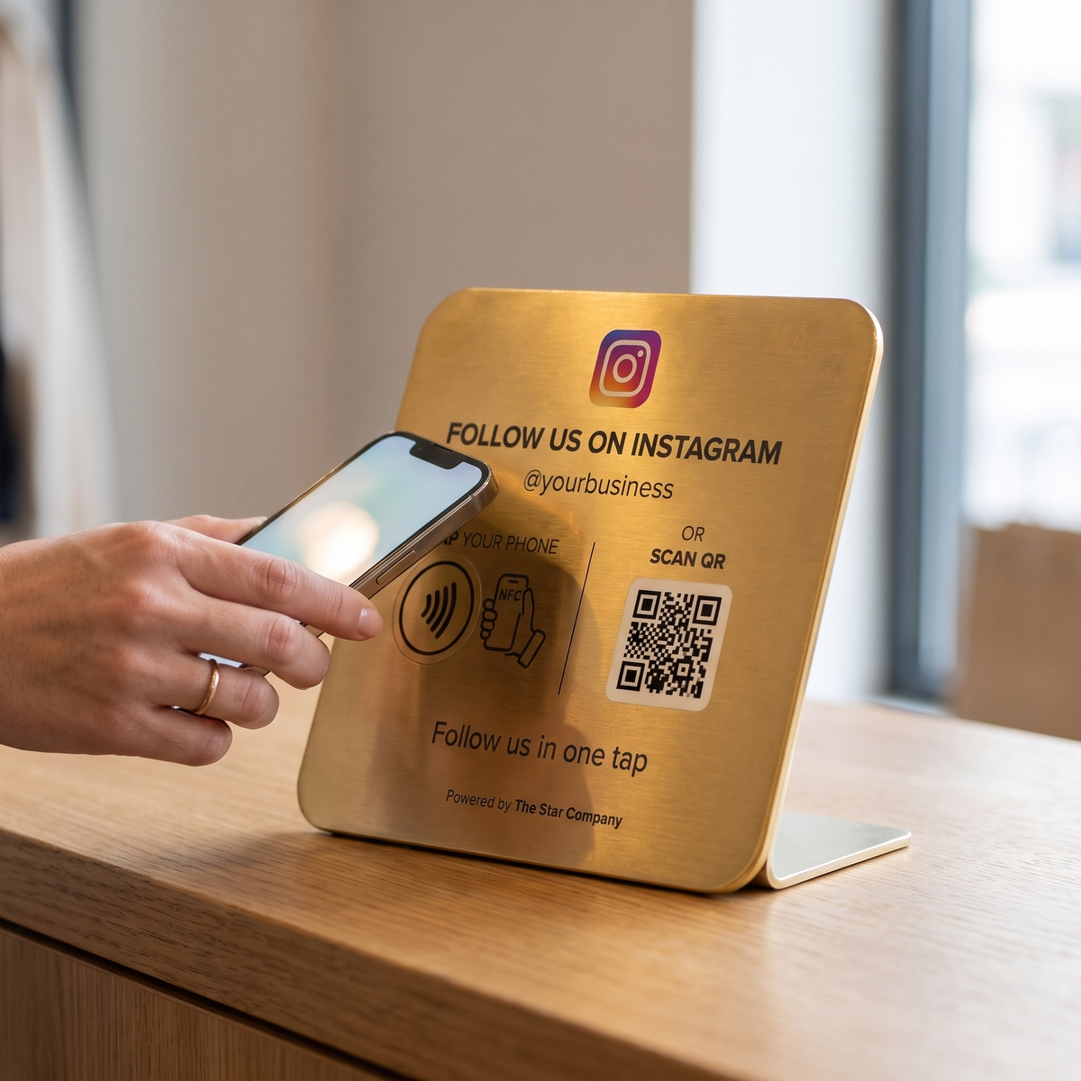 Customer tapping a phone to the 22K gold Instagram Follow Plate at a boutique checkout counter