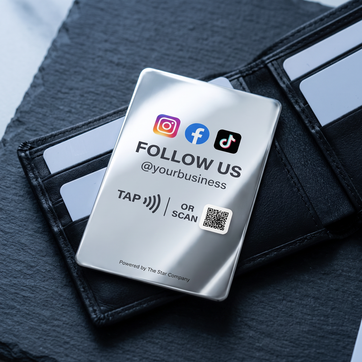 Stainless steel Social Media Follow Card tucked into a black leather wallet, showing credit-card size